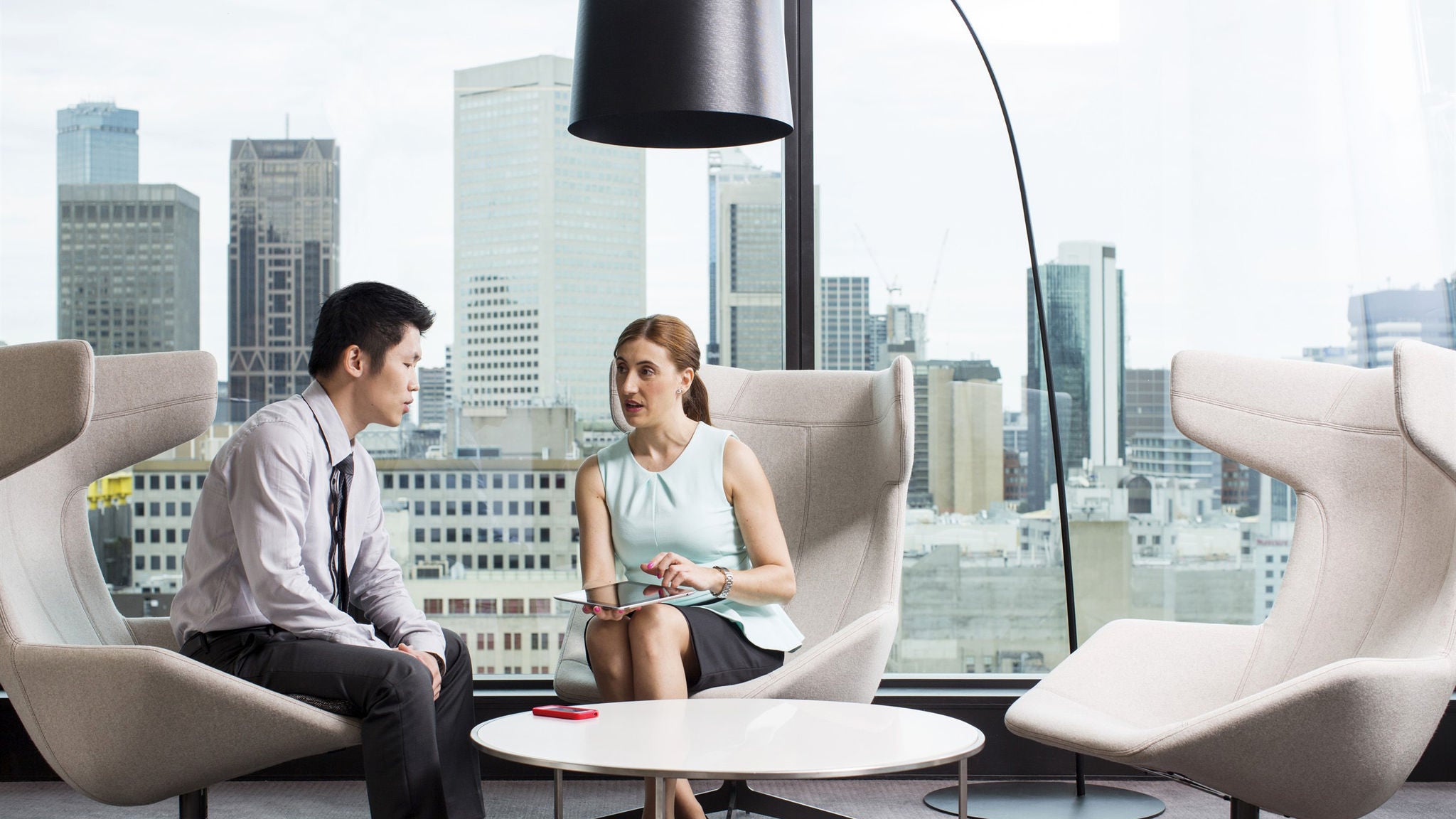 A man and a woman sitting in armchairs in a support centre having a conversation