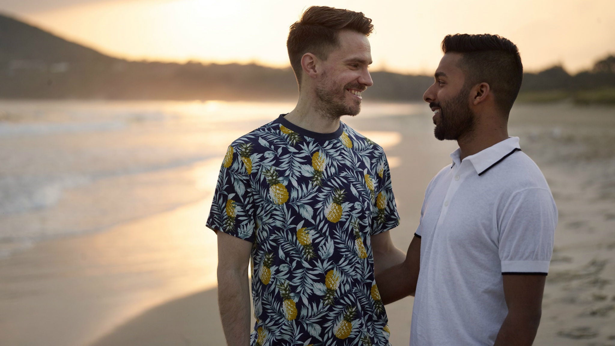 Two men walking along a beach at sunset