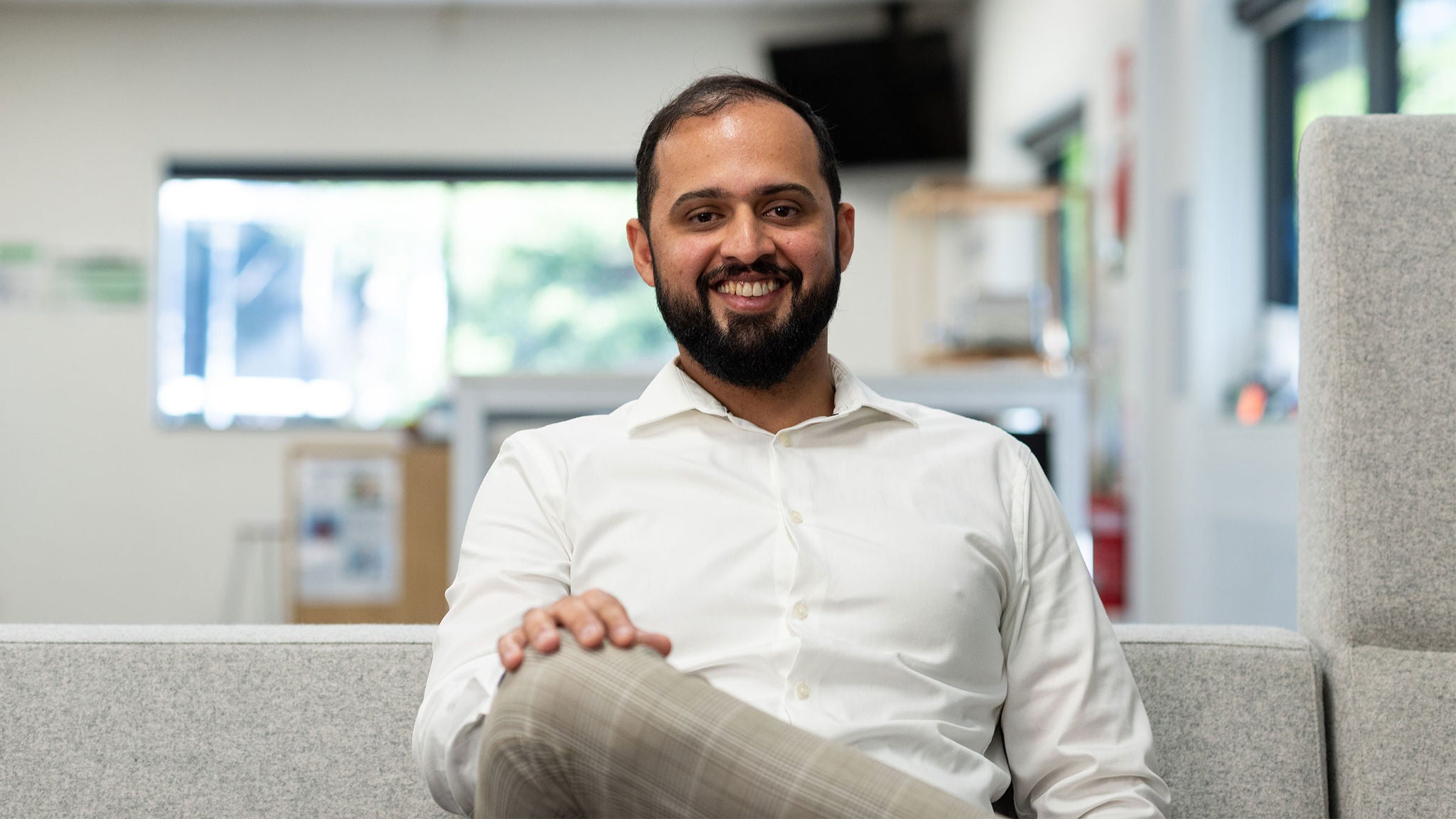 photo-smiling-man-sitting-on-a-couch-arslan-ahmad