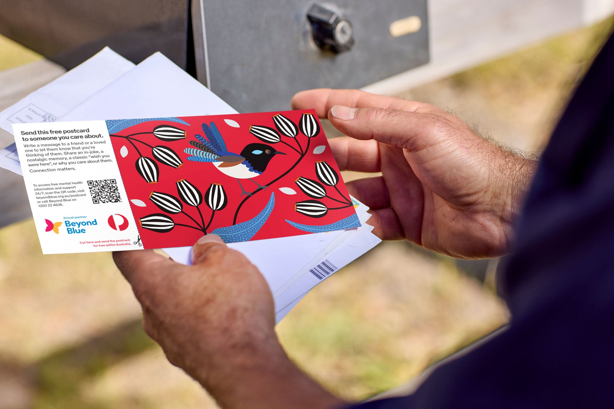 man holding a beyond blue postcard