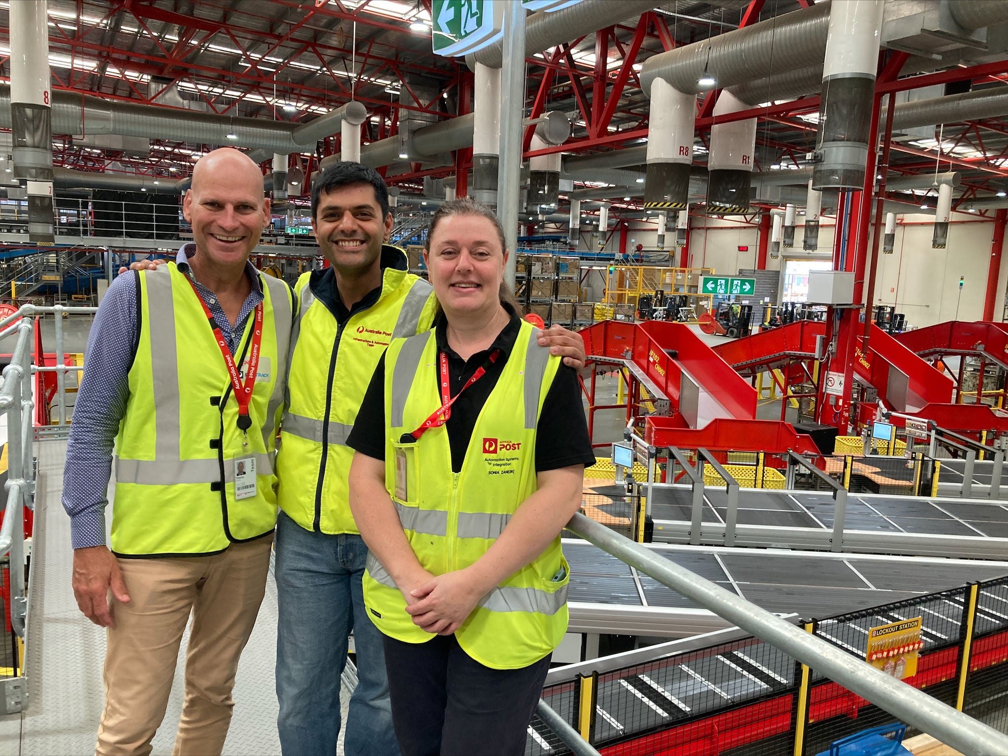 three people in hi-vis in a processing facility