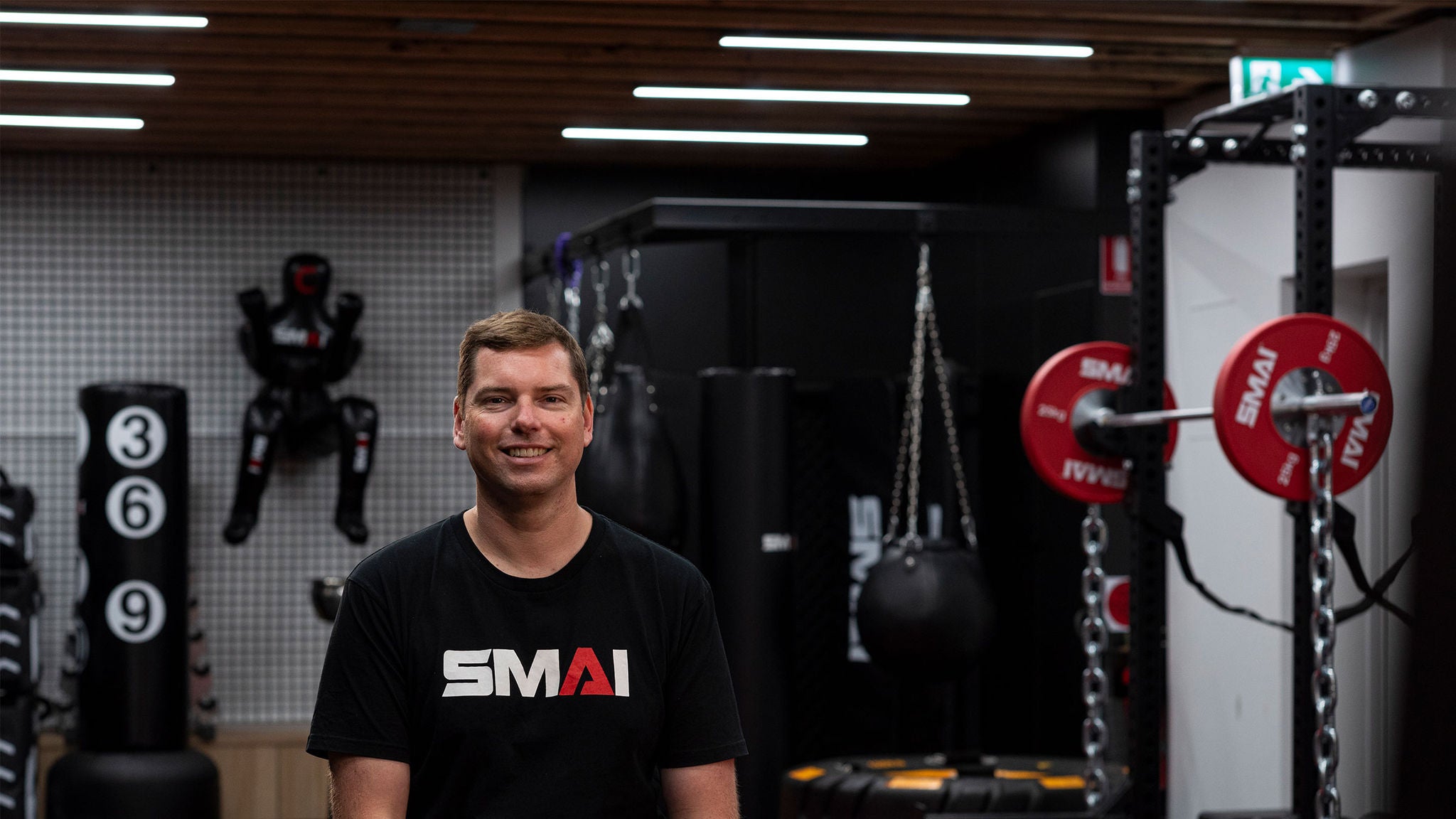 photo-man-in-a-t-shirt-with-the-smai-branding-sitting-in-a-martial-arts-gym