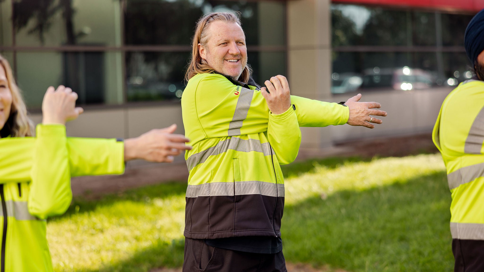 Team members doing pre-shift stretches on the lawn