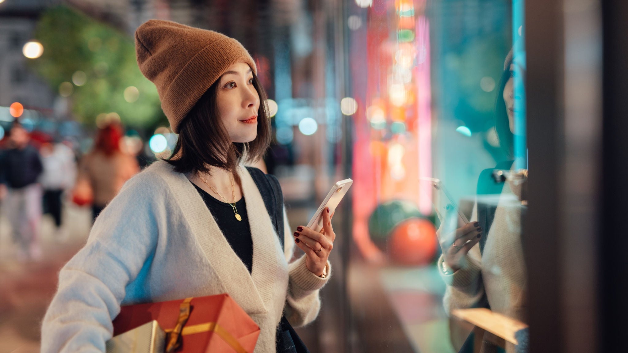 photo-woman-holding-presents-and-phone-looking-in-store-window