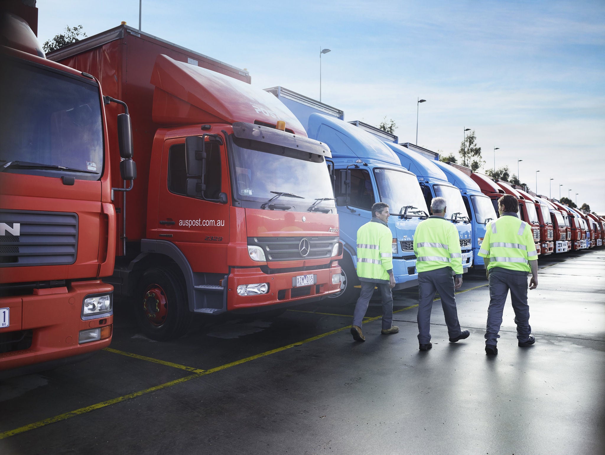 Drivers walking in front of Australia Post and StarTrack trucks