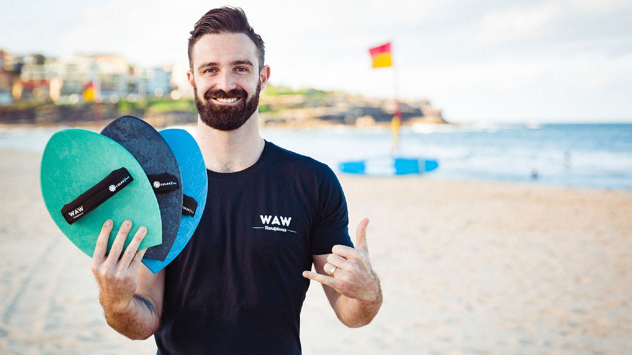 photo-man-standing-on-beach-holding-waw-handplanes