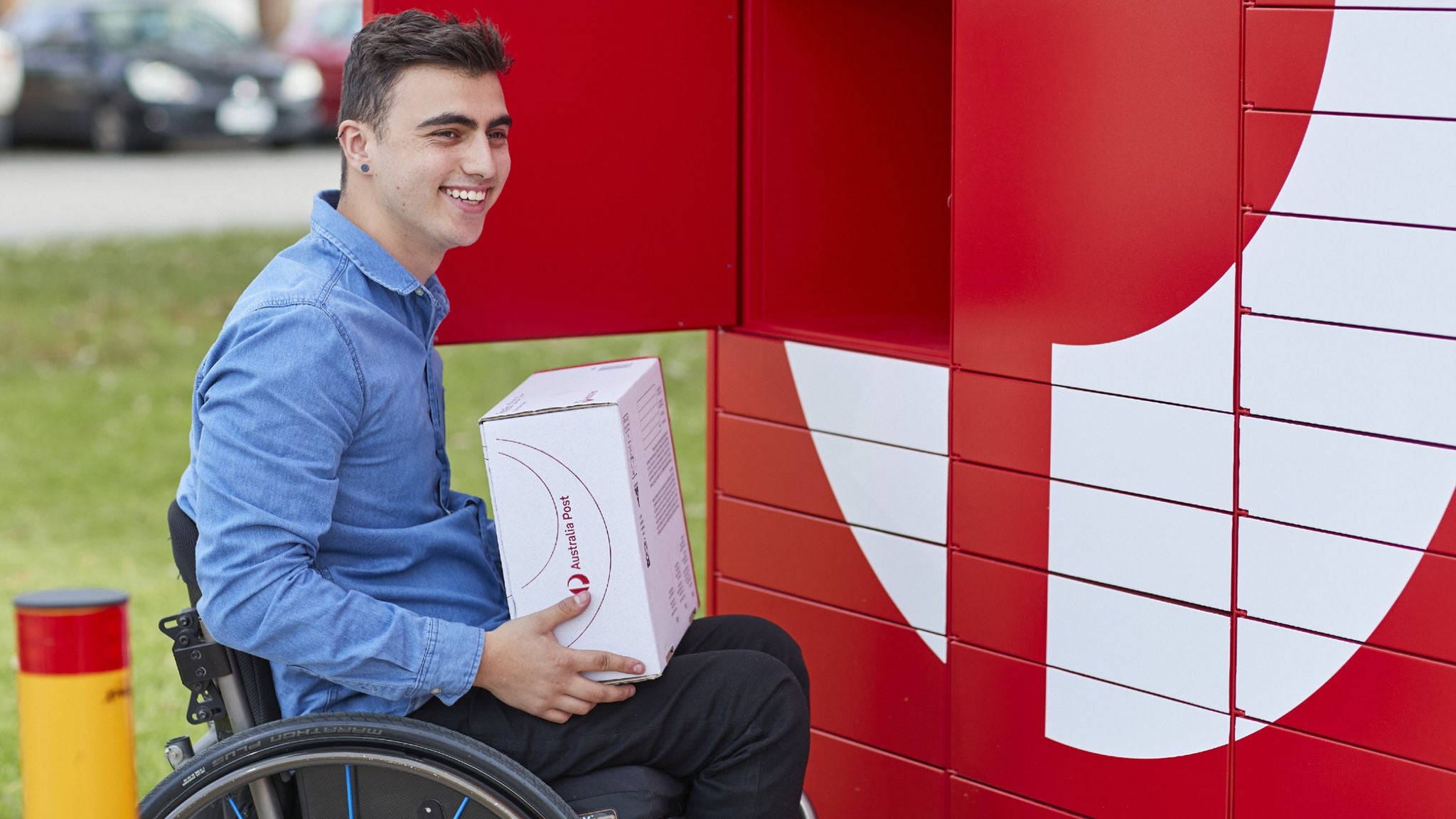 photo-man-in-wheelchair-holding-box-in-front-of-parcel-lockers
