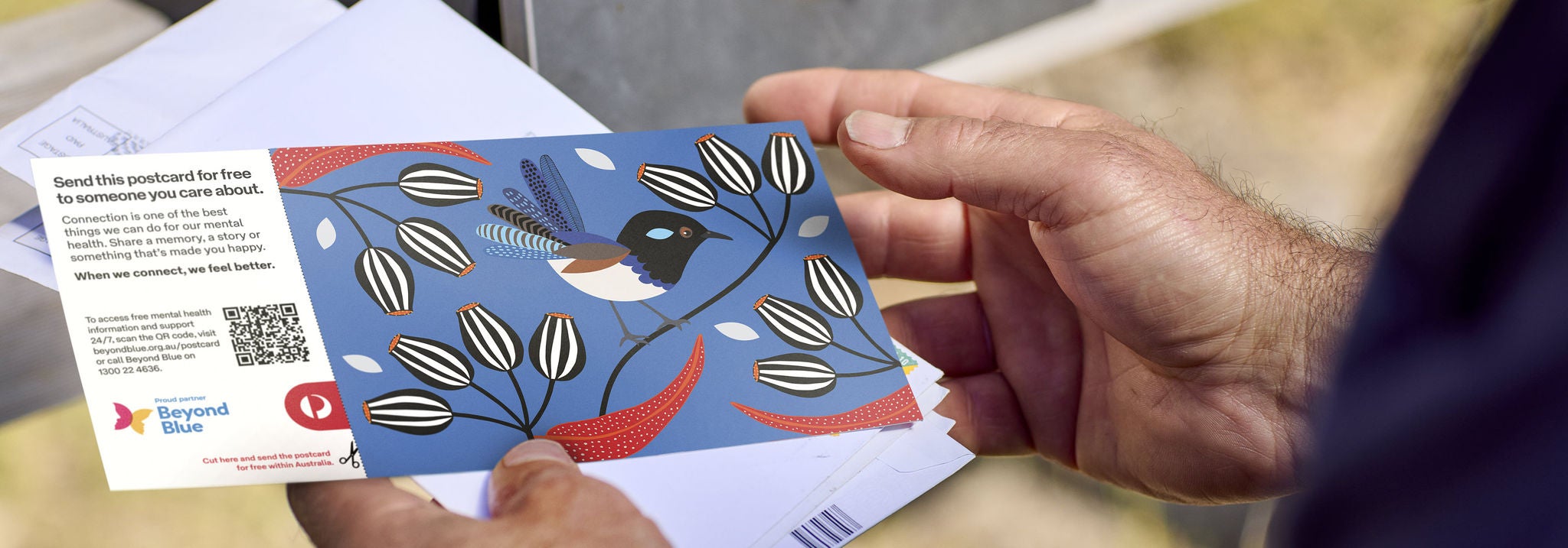 A person holding a Beyond Blue postcard