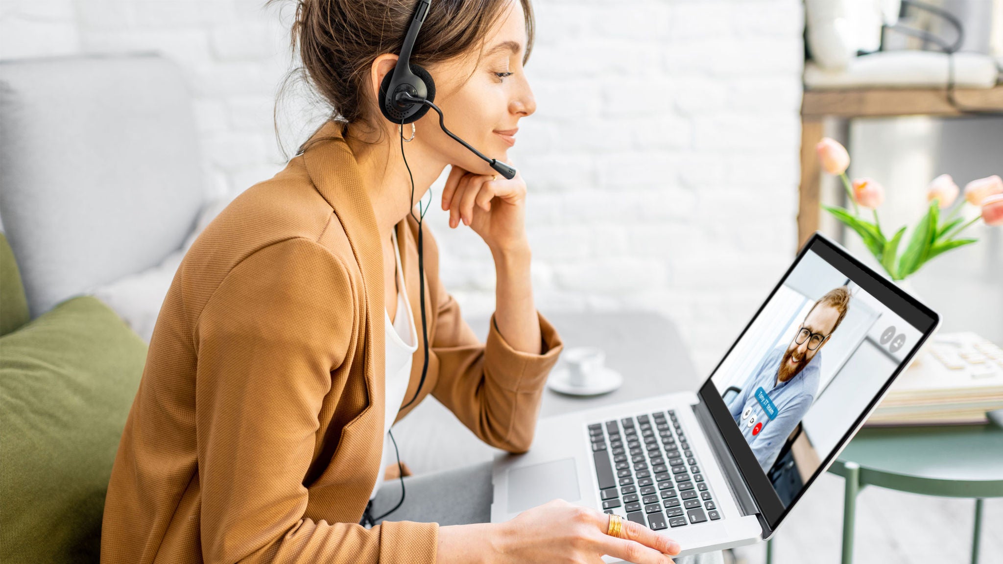 Woman sitting at a desk on a laptop wearing a headset
