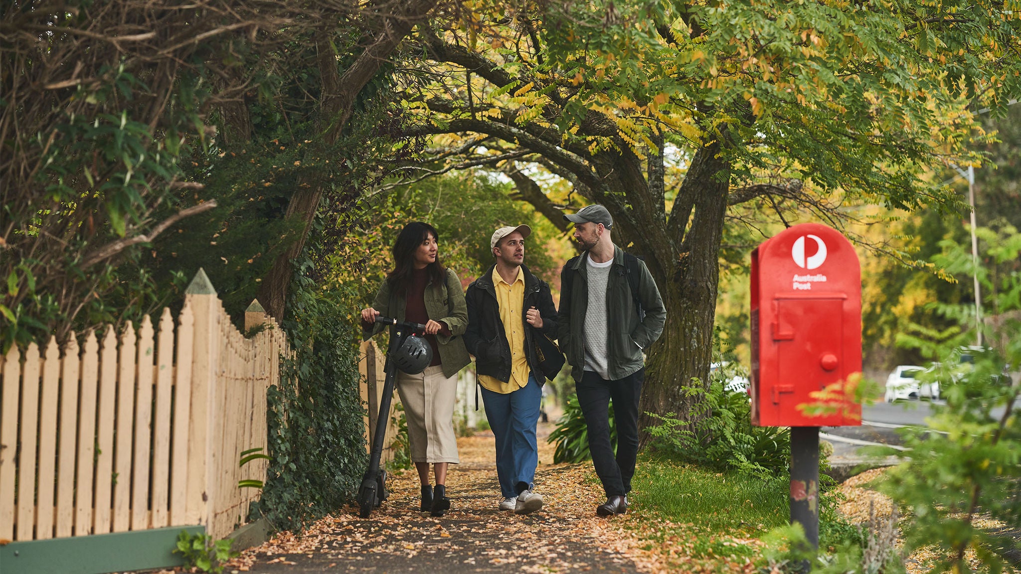 photo-three-people-walking-on-sidewalk-trees-red-street-posting-box-spb